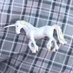 Small toy unicorn that is white with a tint of yellow!